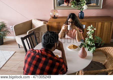 Young Diverse Loving Couple Eating Croissant And Talks Together At Home In Breakfast Time. Communica