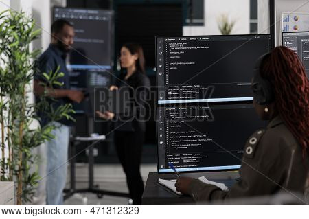 Multi Ethnic Team Of Software Developers Analyzing Code On Wall Screen Tv, Using Digital Device And 