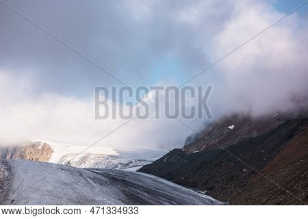 Scenic Mountain Landscape With Large Glacier In Low Clouds In Sunrise Colors. Colorful View To Glaci
