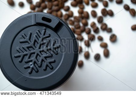 Winter Cup Among Coffee Beans. A Plastic Cup Among Coffee Beans. Plastic Cover About A Snowflake On