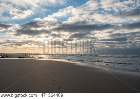Sandy Beach At The Sea Under A Sky Painted With Clouds And A Golden Sun, Showing An Amazing Colorful