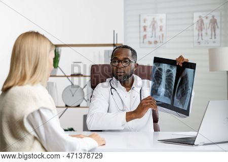 African American Doctor, Receives A Patient, Listens To Complaints, Makes Diagnostics. Writes Data. 