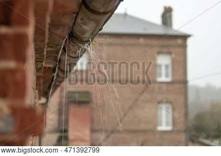 A Gutter On A Building, An Old Drainpipe Close-up, Water Flows Through Rotten Metal, There Is A Plac