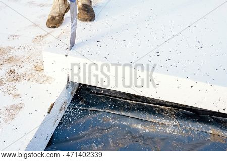 Builder Placing Polystyrene Insulation Boards On Waterproofing Membrane During Floor Construction. E