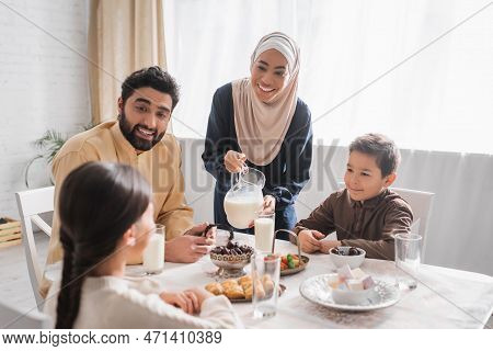 Smiling Muslim Family Looking At Daughter During Suhur Breakfast At Home.