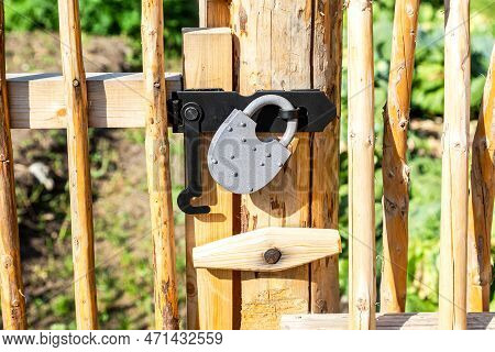 New Metal Padlock On A Bright Yellow Wooden Fence In The Village