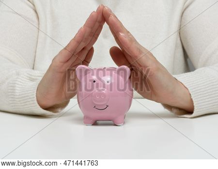 A Ceramic Piggy Bank And Female Hands Above It, A Concept Of Saving Money