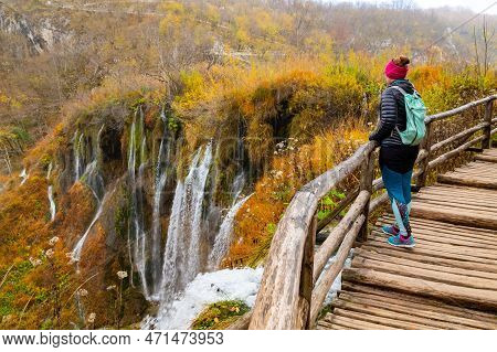 Young Woman Tourist Walking In Plitvice Lakes National Park During Colorful Autumn, Croatia, Europe.