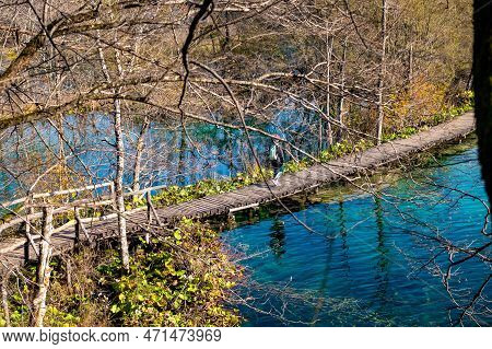 Young Woman Tourist Walking In Plitvice Lakes National Park During Colorful Autumn, Croatia, Europe.