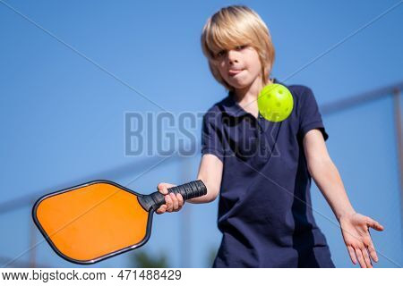 Happy Blonde Boy Playing Pickleball Game, Hitting Pickleball Yellow Ball With Paddle, Outdoor Sport 