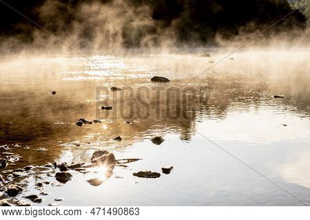 Warmy Golden Haze Above Lake Water In Early Morning In Bright Yellow Sunlight With Sun Glares And Bl