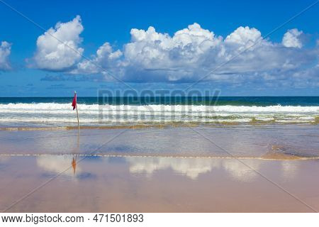Red Flag With Waves And Clouds Reflecting In The Sand, Sao Jose Beach, Itacare, Bahia, Brazil