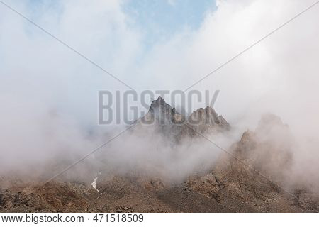 Scenic Alpine Landscape With Rocky Mountains In Dense Low Clouds In Morning Sunlight. Colorful Mount