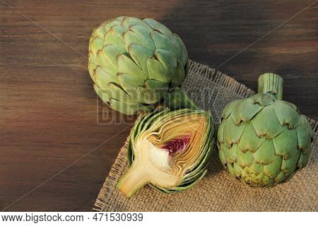 Whole And Cut Fresh Raw Artichokes On Wooden Table, Flat Lay