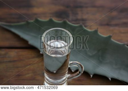 Mexican Tequila Shot And Green Leaf On Wooden Table, Closeup. Drink Made Of Agava