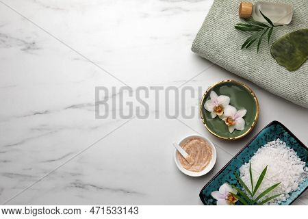 Flat Lay Composition With Different Spa Products And Flowers On White Marble Table. Space For Text