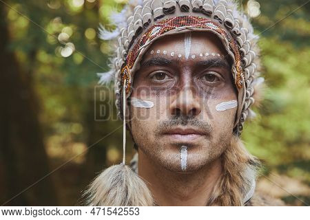 A Man In Traditional Native American Clothing In The Evening Forest