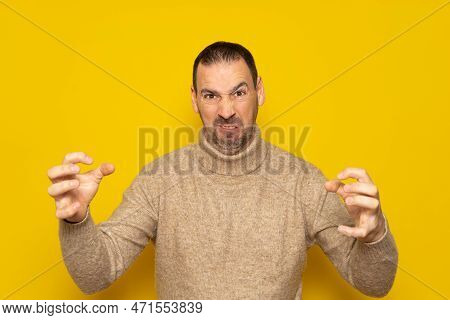Hispanic Man With Beard Over Isolated Yellow Background In Aggressive And Furious Attitude With Rais