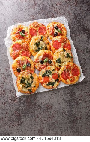 Mix Mini Pizza Or Pizzette With Various Toppings Close-up On Parchment On The Table. Vertical Top Vi