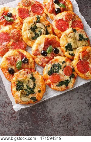 Pizzette Small Pizzas With Various Toppings Close-up On Parchment On The Table. Vertical Top View Fr