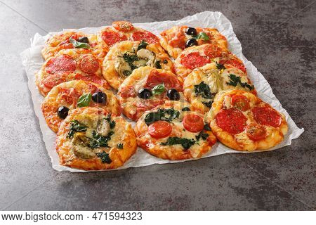 Hot Assorted Mini Pizza Or Pizzette With Various Toppings Close-up On Parchment On The Table. Horizo