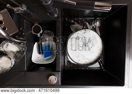 Washing Dishes Concept. Dirty Dishes With Foam From Detergent In A Black Stone Sink In The Kitchen T