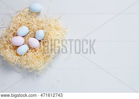 Bblue And Pink Pastel Color Easter Eggs In A Nest On A White Wooden Background. Top View With Copy S