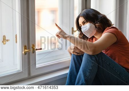 Quarantive Concept. Arab Female Wearing Protective Mask Sitting Near Windor At Home