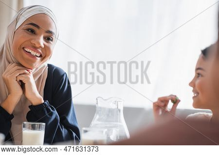 Happy African American Mother In Hijab Looking At Blurred Kids During Suhur At Home.