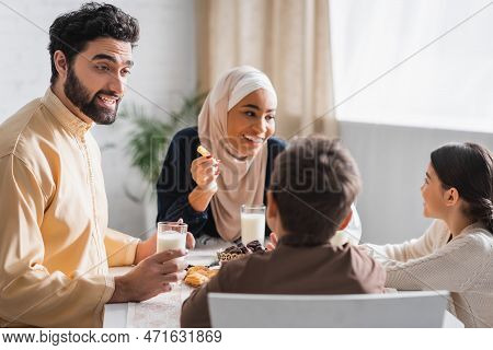 Muslim Father Talking To Son Near Happy Family During Suhur Breakfast.