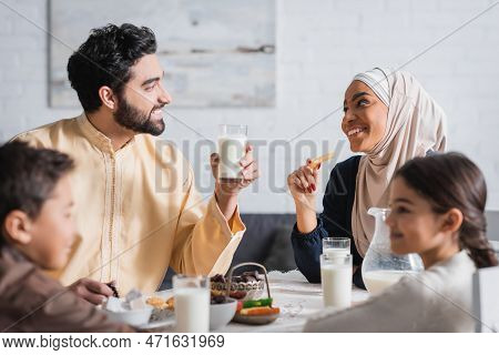 Happy Muslim Parents Looking At Each Other Near Blurred Kids And Suhur Breakfast At Home.