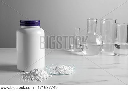 Calcium Carbonate Powder, Jar And Laboratory Glassware On White Marble Table. Space For Text