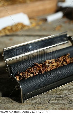 Roller With Tobacco On Old Wooden Table, Closeup. Making Hand Rolled Cigarettes