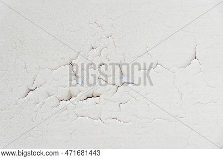Close-up. Badly Fixed Building Facade Wall Covered With Cracks In Stucco And Paint. Missing Patch Of