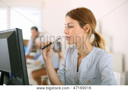 Chica fumando con el cigarrillo electrónico en la oficina