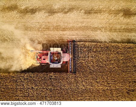 Aerial Drone Photo Of Red Harvester Working In Wheat Field On Sunset. Top View Of Combine Harvesting