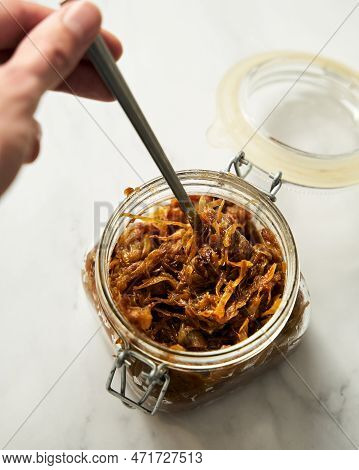 Homemade Caramelized Onions In The Jar. Mans Hand With Spoon Reaches Into The Jar
