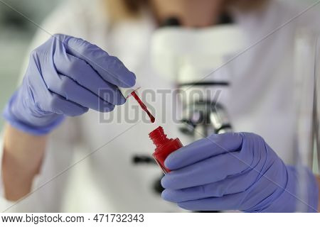 Close-up Of Woman Lab Assistant Holding Bottle Of Nail Polish In Hands. Chemical Analysis Concept