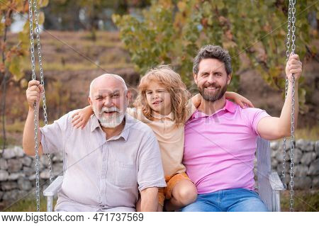 Men Generation: Grandfather Father And Grandson Are Swinging, Looking At Camera And Smiling. Fathers