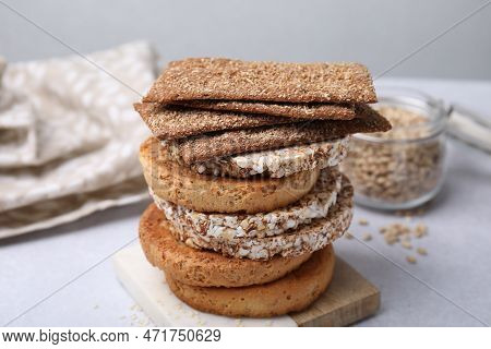 Stack Of Rye Crispbreads, Rice Cakes And Rusks On White Table