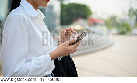 Cropped Side View Image Of A Gorgeous Asian Businesswoman Using Her Smartphone On The Street.