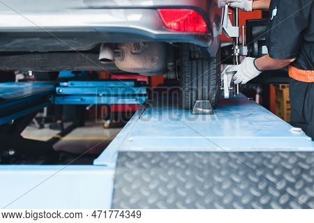 In The Service Station Workshop, A Car Is On A Stand With Sensors On The Wheels Being Checked For Wh