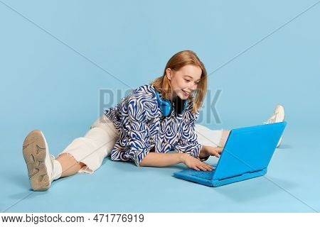 Happy Smiling Beautiful Young Girl, Student Working, Studying And Communicating On Laptop Over Blue 