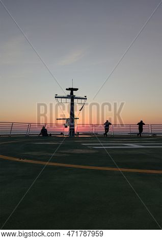 People Enjoying Sunset On The A Helipad Of A Cruise Ship