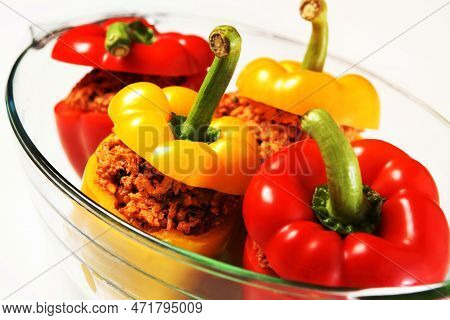 A Picture Of An Unbaked Yellow And Red Stuffed Peppers Served In A Heatproof Glass