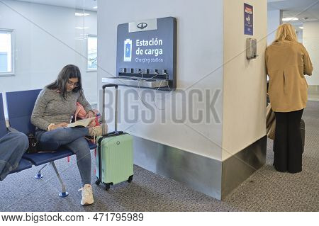 Buenos Aires, Argentina, November 18, 2022: Young Woman Reading A Book Next To An Electric Charging 
