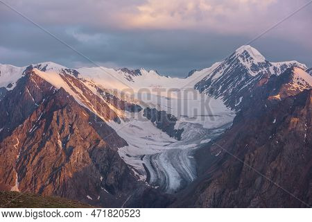 Dramatic Aerial View To High Snow Mountain Peak In Early Morning At Dawn. Awesome Scenery With Sunli