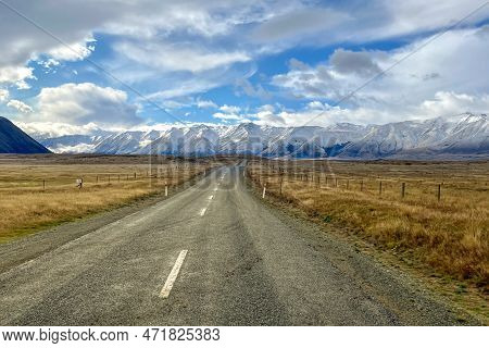 The Long Country Road Winding Its Way Through The Grass And Tussock Valley Being Grazed By Farmers O