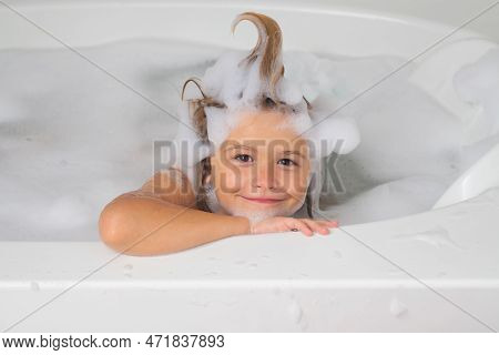Kids Bath. Kid Washing With A Bubbles In Bath. Cute Child Bathes, Lying In A White Bath With Foam Fr