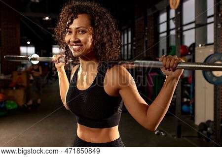 Portrait Of Young African American Woman Lifting Barbell While Exercising In Crossfit Gym. Self-moti